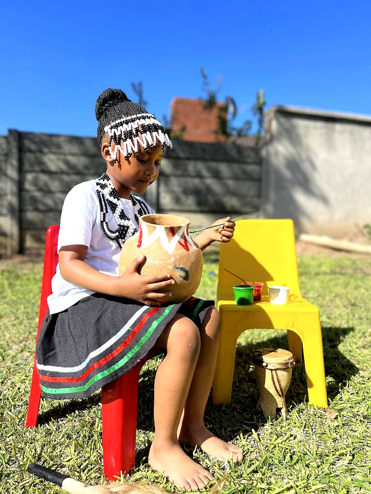 A learner painting traditional patterns on a clay pot